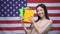 Asian girl smiling against USA flag background, student holding copybooks