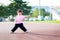 Asian girl is standing in stadium for exercise. Child stand with their legs and arms extended. Happy kid is 4 year old.