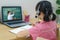 Asian girl student video conference e-learning with teacher and classmates on computer in living room at home. Homeschooling and