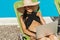 asian girl in swimsuit and straw hat using laptop on sunbed