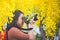 Asian girl take photo with blooming yellow flower