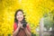 Asian girl take photo with blooming yellow flower