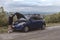 An asian girl talks to a mechanic describing the situation of her car trouble. Emergency roadside call. Stranded at a rural area