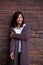 Asian girl in warm purple cardigan near brick wall