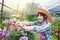 An Asian girl who owns an orchid farm wears a hat.
