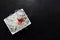 Asian glass rice noodles with vegetables and herbs on a white deep square plate on a black slate background with place for text.