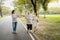 Asian granddaughter,daughter assisting senior mother to walking follow white line on the floor with the support at park, female