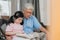 Asian grandfather relax at home. Senior Chinese, grandpa happy relax with young granddaughter girl enjoy read books and do