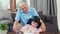 Asian grandfather teach granddaughter drawing and doing homework at home. Senior Chinese, grandpa happy relax with young girl