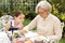 Asian grandmother is drawing outside with granddaughter. Casual, outdoors