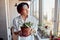 Asian guy looking at the view of the city and holding a flowerpot