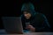 Asian hacker hacking computer network with laptop in dark. Cyber security concept