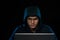 Asian hacker hacking computer network with laptop in dark. Cyber security concept