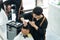 Asian hairdresser barber male cut hair of attractive man in salon shop. Professional hairstylist combing and using scissors give