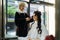 Asian hairdresser curls hair for customer with ceramic curler at beauty salon