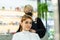 Asian hairdresser wear mask, cutting hair of beautiful woman in salon. Caucasian customer girl enjoy beauty barber shop service,