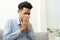 Asian handsome of  man having  flu season and sneeze using paper tissues sitting on sofa at home, Health and illness concepts