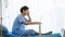 Asian handsome stress male patient wearing blue uniform, getting sick or illness, busy working, using laptop, sitting on bed in