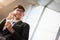 A asian handsome young businessman holding his hot coffee cup while using his phone and standing on the escalator. Business