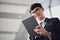 A asian handsome young businessman using his tablet and standing on the escalator. Business concept