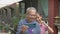 Asian happy elderly gray hair grandfather in eyeglasses holding mobile smartphone enjoy taking selfie photo and filming video.