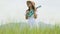 Asian happy woman in white dress playing ukulele guitar in green meadow field with mountaing background on summer. Musician beauty