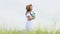 Asian happy woman in white dress playing ukulele guitar in green meadow field with mountaing background on summer. Musician beauty