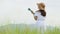 Asian happy woman in white dress playing ukulele guitar in green meadow field with mountaing background on summer. Musician beauty