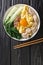 Asian homemade egg noodle soup with anchovies, meatballs and bok choy close-up in a bowl. vertical top view