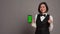 Asian hotel concierge pointing at phone with greenscreen layout