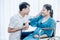 Asian husband and wife are pregnant, and sitting in a wheelchair they are smiling and happy together