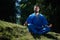 Asian Kazakh karate fighter is meditate in blue kimono uniform on a summer beautiful nature landscape