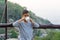 Asian kid boy is drinking water from the glass. With mountain views background