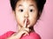 Asian kid girl in pink sweater shows shhh quiet sign on pink