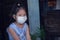 Asian kid girl wearing a medical mask protect coronavirus, sitting alone, looking at camera with copy space