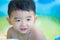 Asian kid playing in inflatable baby swimming pool on hot summer