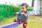 Asian kid riding seesaw board at the playground under sunlight,