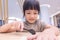 Asian kid using spoon to eat in restaurant