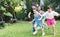 Asian kids playing outdoors with friends. little children play football soccer at nature park.