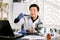 Asian Korean male doctor biochemist scientist in white coat and protective gloves holding test tube with red liquid