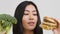 Asian Lady Choosing Unhealthy Burger Instead Of Broccoli, White Background