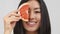 Asian Lady Holding Grapefruit Half-Slice Near Face Posing, White Background