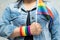 Asian lady wearing blue jean jacket or denim shirt and holding rainbow color flag, symbol of LGBT pride month celebrate annual in