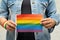 Asian lady wearing blue jean jacket or denim shirt and holding rainbow color flag, symbol of LGBT pride month celebrate annual in