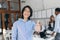 Asian laughing boy posing with thumb up at the beginning of the workday. Chinese office worker in blue shirt and glasses