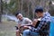 Asian LGBTQ couple enjoying nature, camping with tents in the forest area by the river, playing guitar.