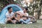 Asian LGBTQ couple enjoying nature, camping with tents in the forest area by the river, playing guitar.