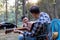 Asian LGBTQ couple enjoying nature, camping with tents in the forest area by the river, playing guitar.