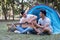 Asian LGBTQ couple enjoying nature, camping with tents in the forest area by the river, playing guitar.