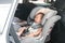Asian little baby child fastened with security belt in safety car seat